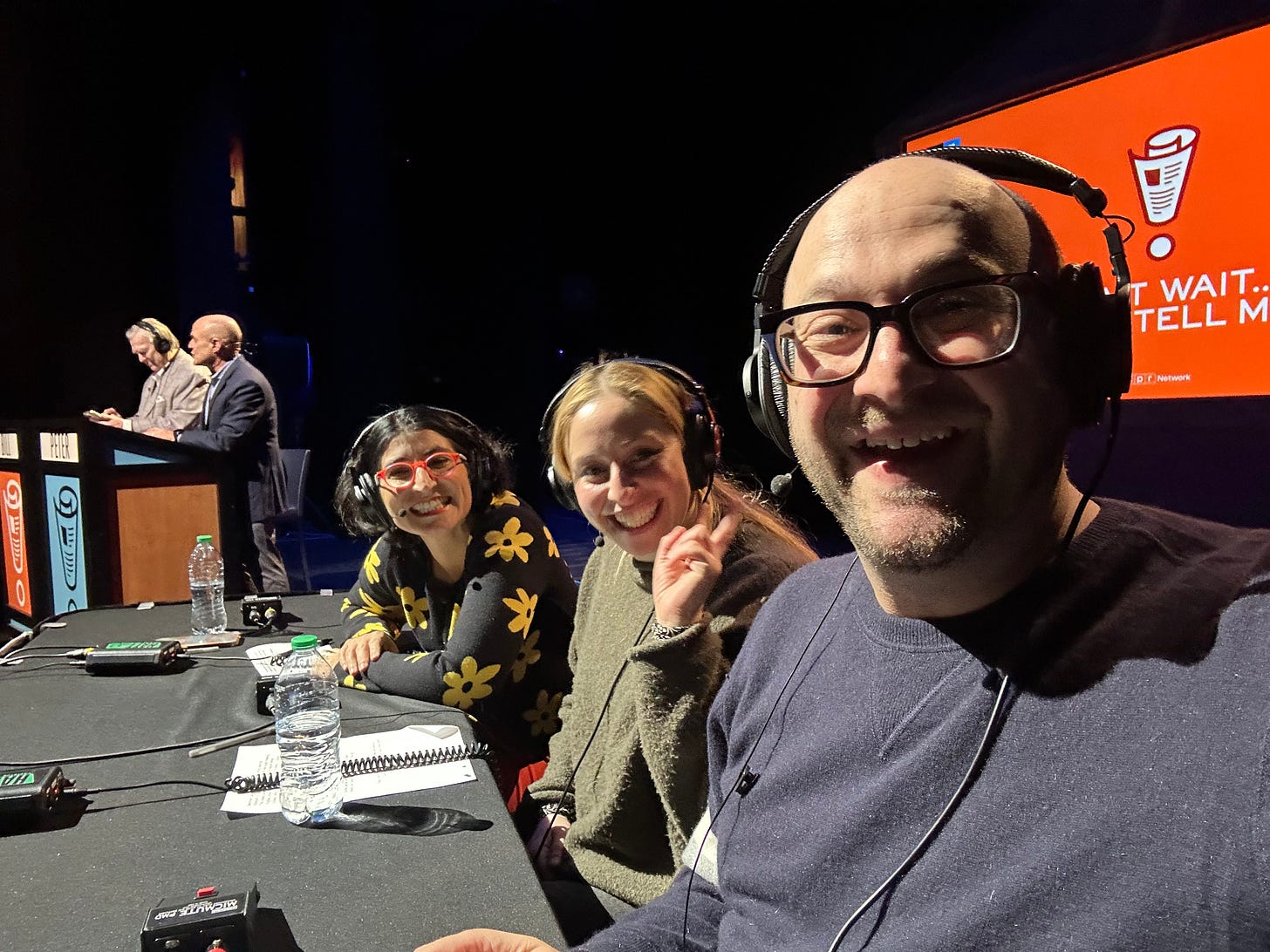 Me, Rachel, and Negin onstage for Wait Wait with Peter Sagal and Bill Kurtis in the background.