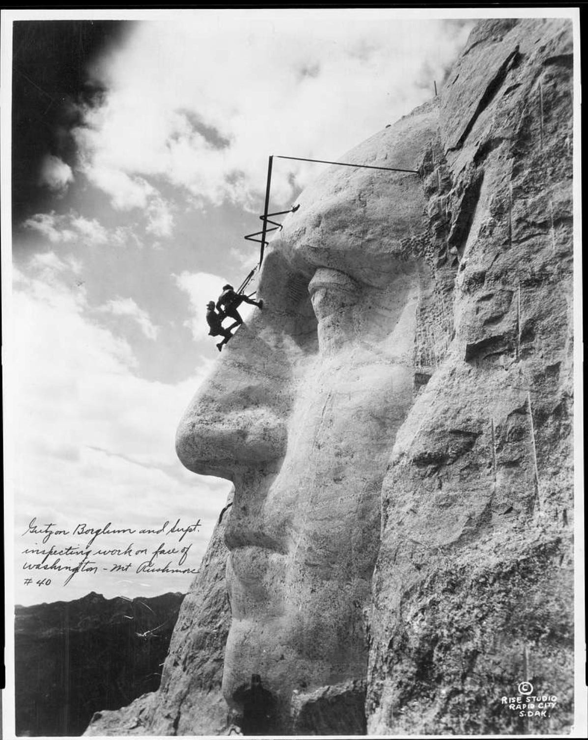 Gutzon Borglum inspects the nose of Geroge Washington on Mount Rushmore.