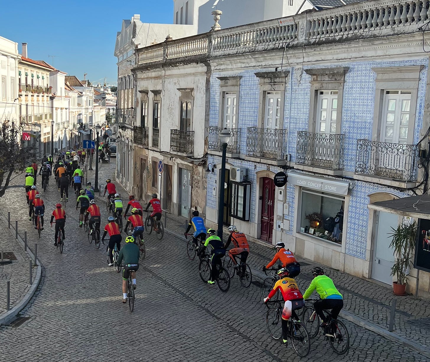Ciclistas com camisolas coloridas a percorrer a rua da cidade velha