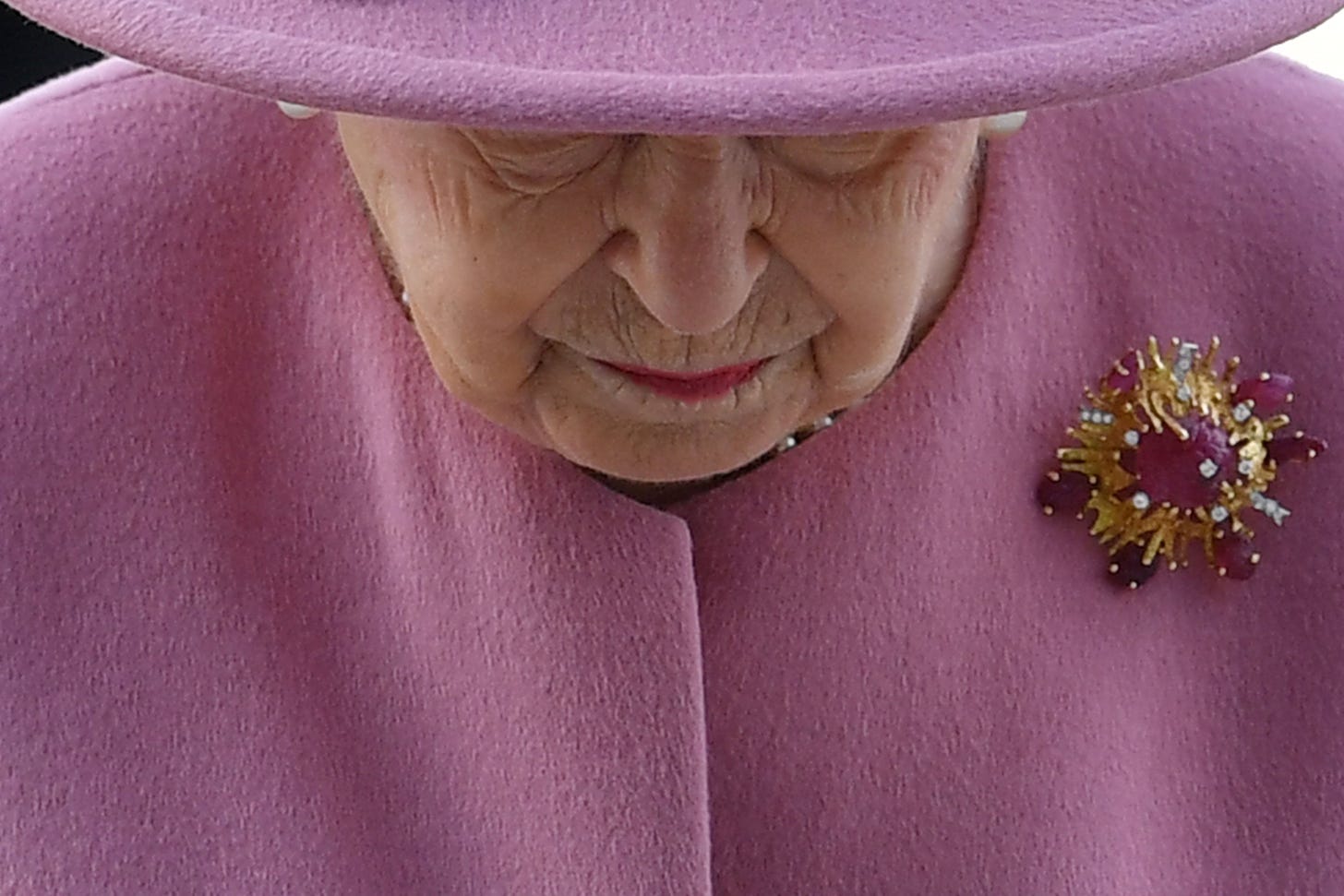 Photo of the Queen looking down wearing pink hat and coat