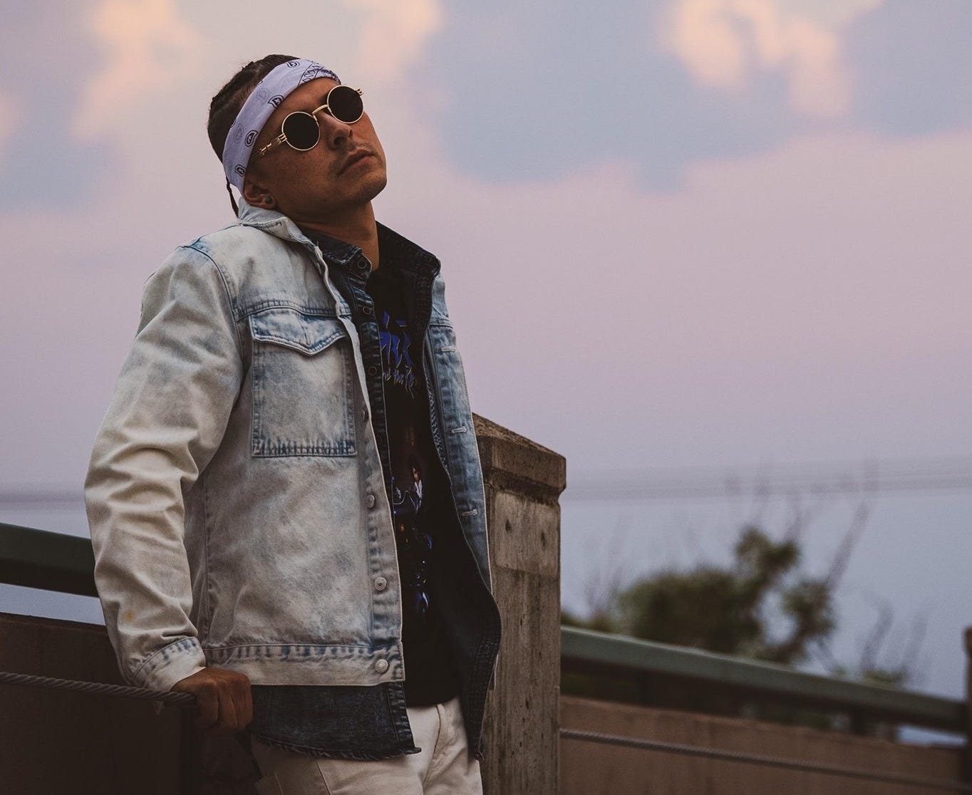 man in denim jacket sunglasses bandana outside at sunset