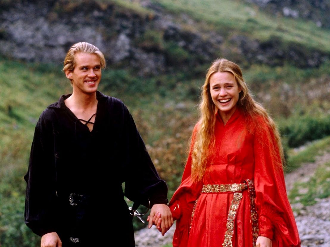 Cary Elwes as Dread Pirate Roberts holding Robin Wright's hand, both of them smiling and laughing on set of The Princess Bride