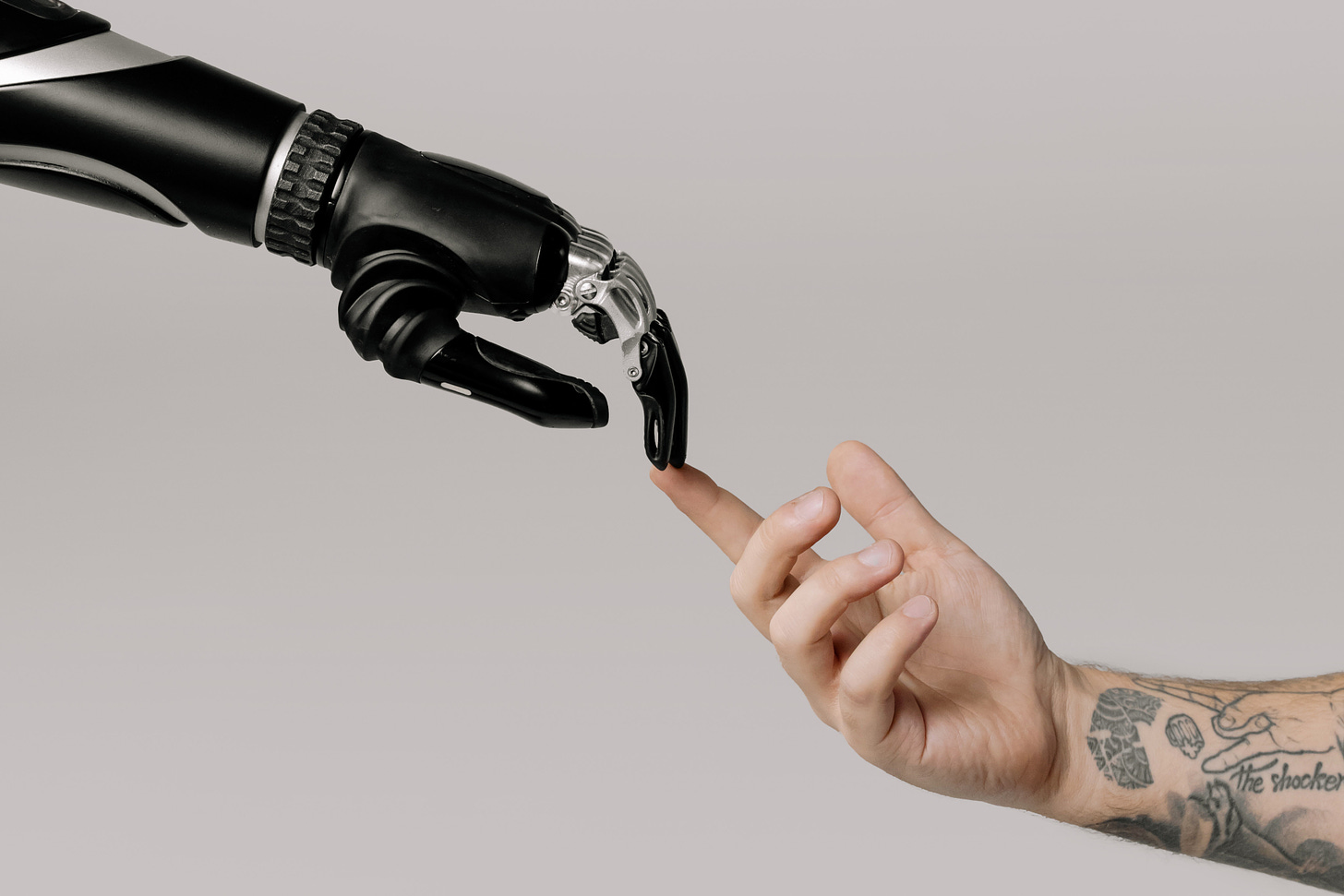 Human arm with tatoos and robot arm touching