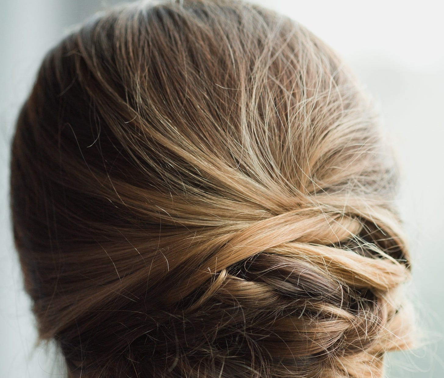 An image of a woman's hair, from behind. It is brunette, and twisted at the nape of her neck.