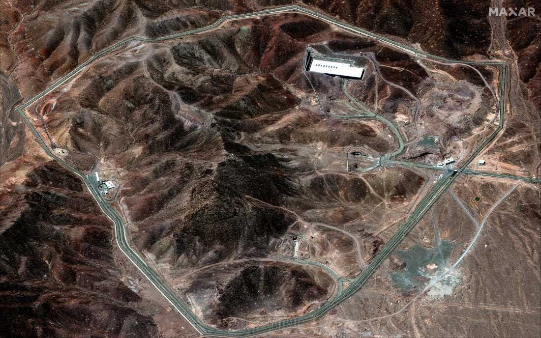 This satellite image shows an area of brown mountains in Iran, with the country's Fordow Fuel Enrichment Plant built into one of the mountainsides. A road roughly circles the perimeter of the image.