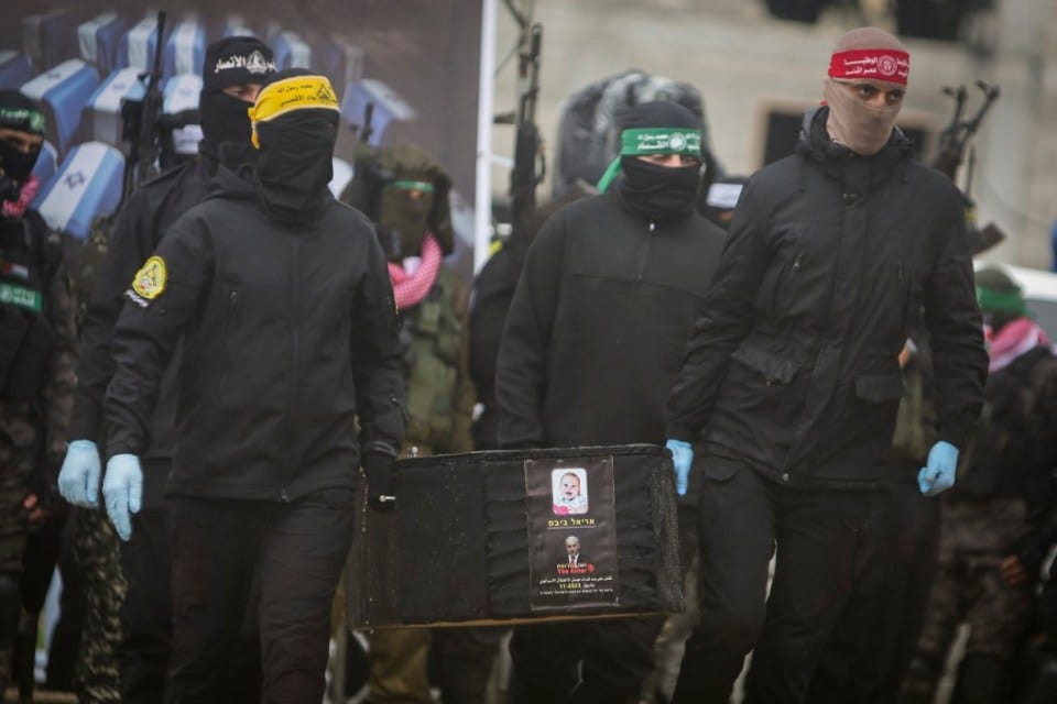 Palestinian fighters carry a coffin containing the body of Kfir Bibas, the youngest captive, one of four Israeli hostages, including Kfir's brother Ariel and their mother Shiri Bibas, being hand it over to the Red Cross in Khan Younis, southern Gaza Strip, Thursday, Feb. 20, 2025. (AP Photo/Jehad Alshrafi)