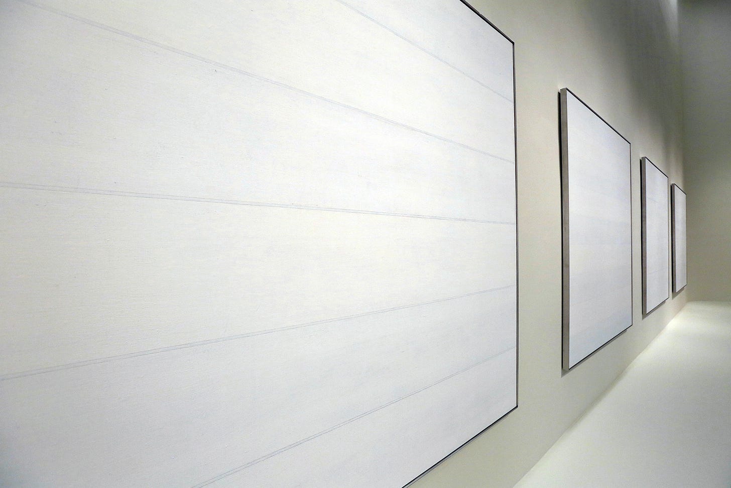 A series of square white and grey paintings by Agnes Martin