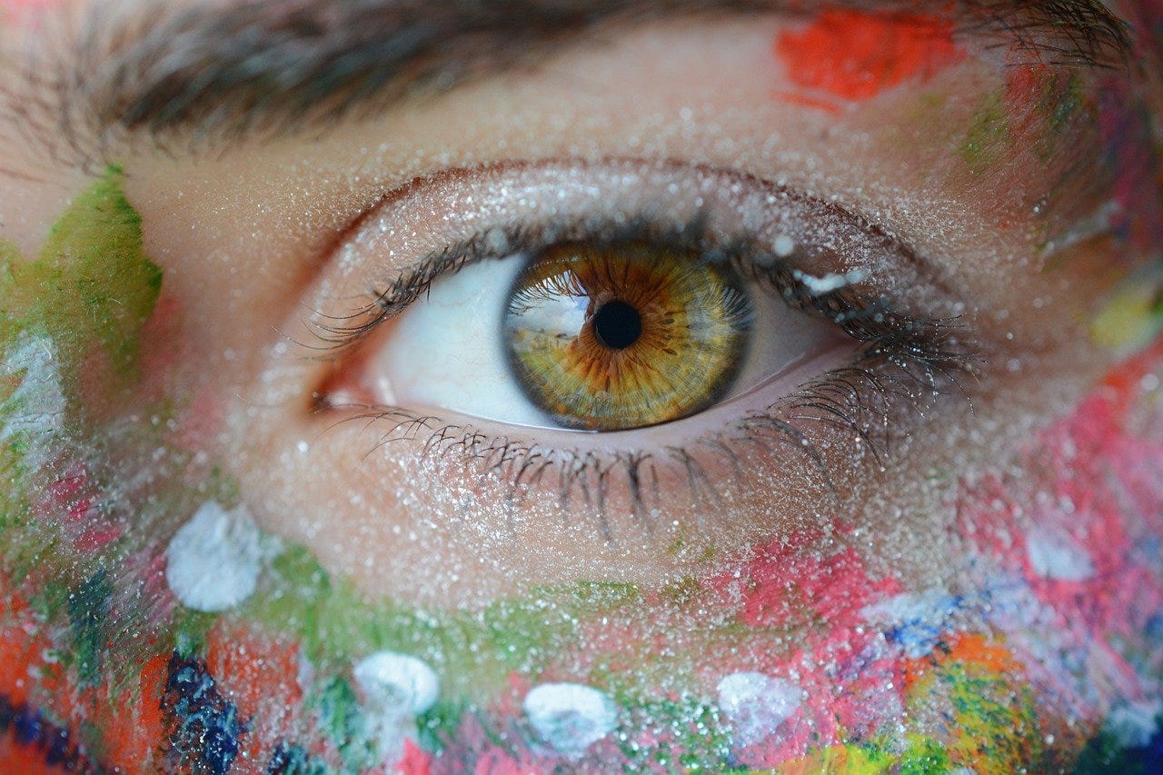 Hazel coloured eye. The skin around the eye is painted in multiple colours