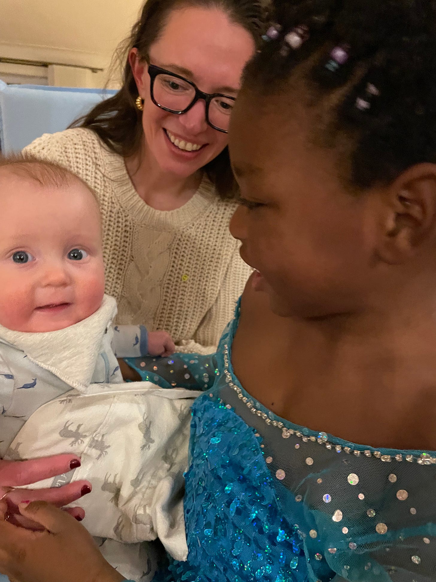 a white baby, Black kid, and white woman smile at each other