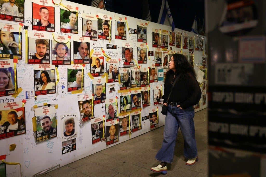A woman walks past posters with in Tel Aviv with images of hostages kidnapped during the Oct. 7 massacre. 