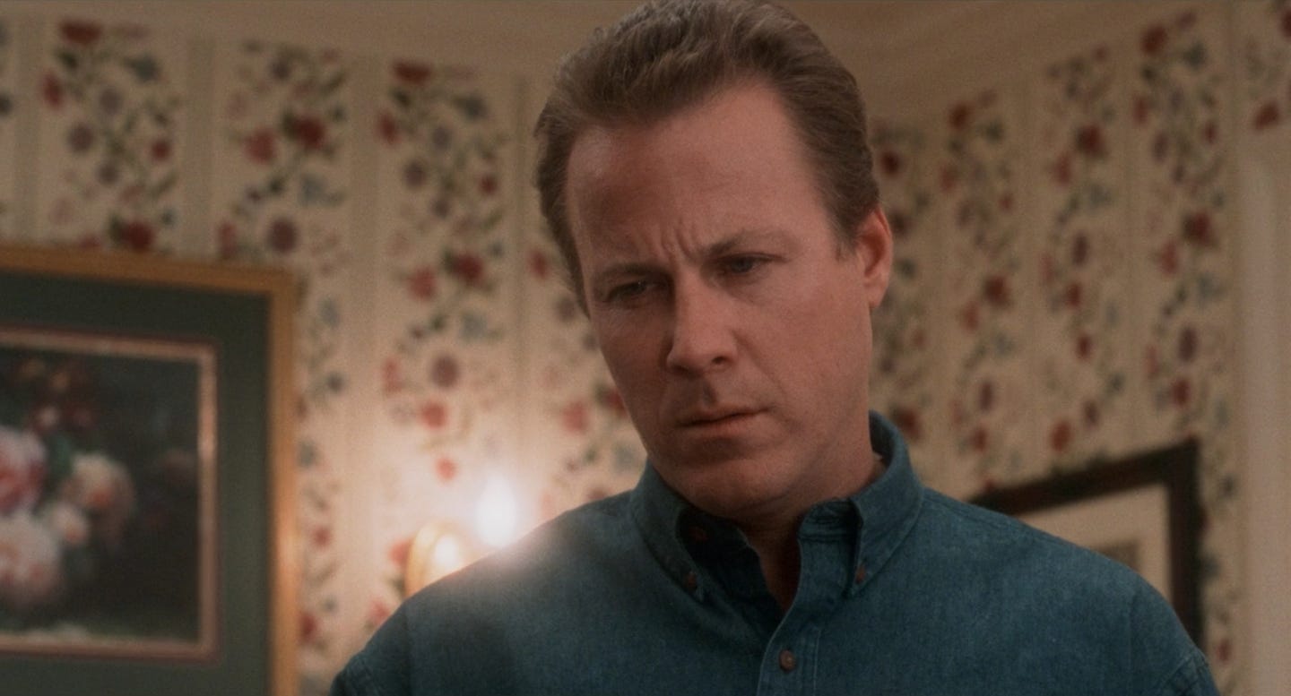 A screen-grab of the character Peter McCallister in Home Alone, as played by the actor John Heard. He is standing in a house and looking smug.