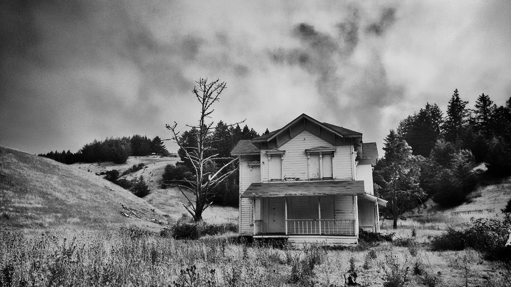 Black and white photo of a dilapidated house in a stark landscape.