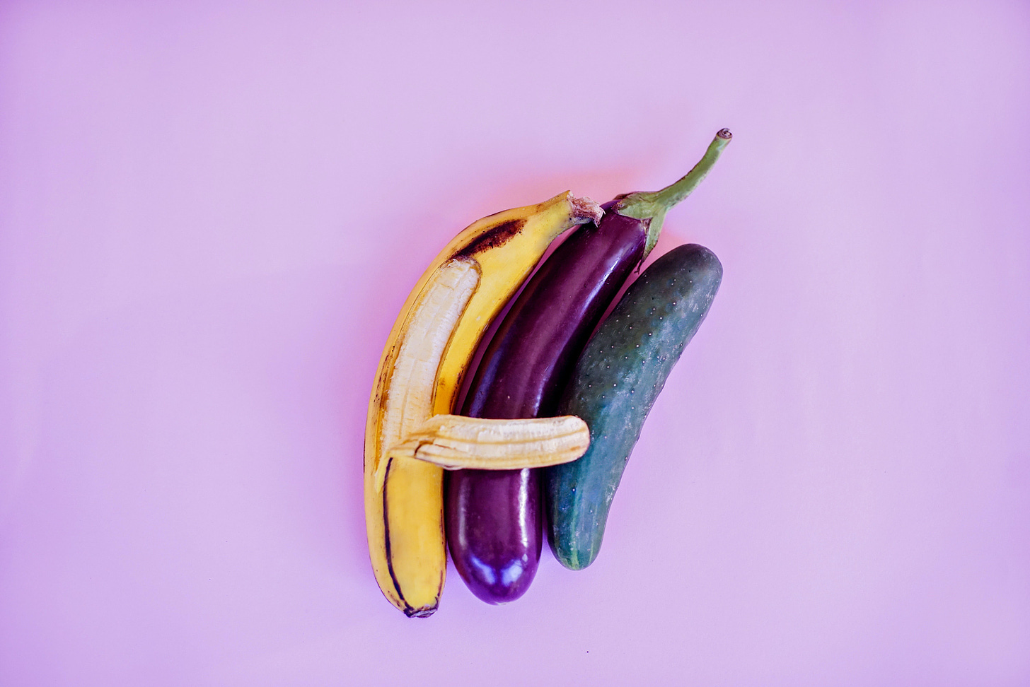 A bananna spooning a cucumber and an eggplant