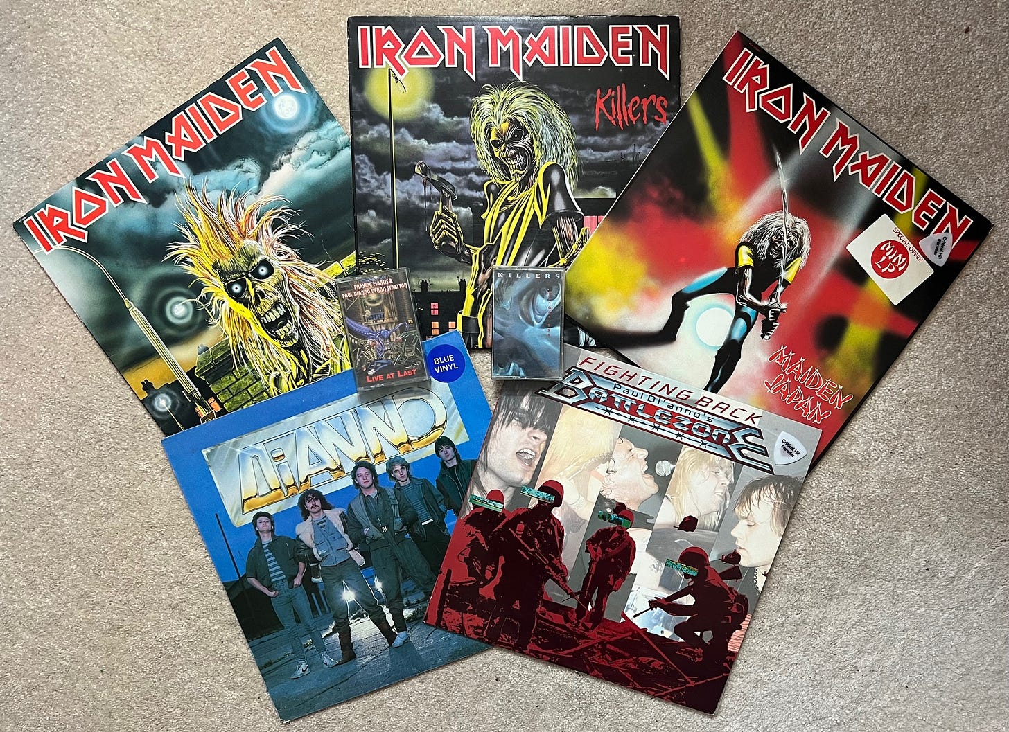 A spread of albums and cassette from Paul Di'Anno projects, including Iron Maiden, Praying Mantis, Di'Anno, Battlezone, and Killers