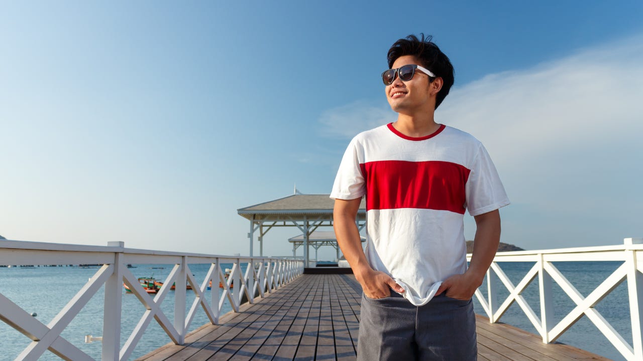 A man wearing sunglasses standing on a pier. 