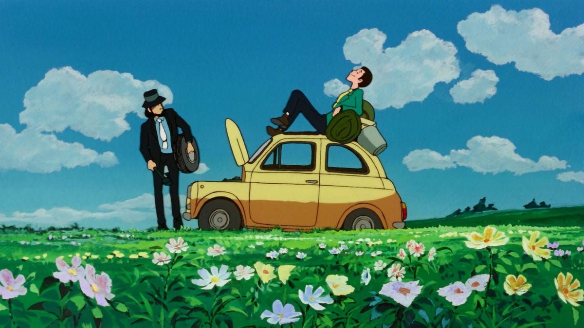 Al centro c'è la fiat 500 gialla con il cofano aperto. Lupin. con giacca verde, è sdraiato sul tettuccio, mentre Jigen è davanti all'auto con uno pneumatico in mano. Attorno a loro un prato fiorito e il cielo limpido con qualche nuvola.