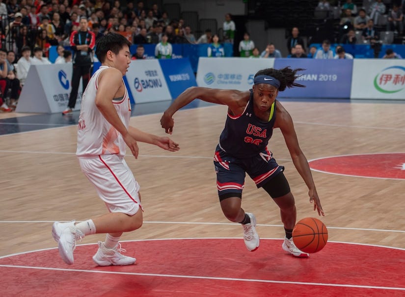 Basketball player drives the lane against a defender.