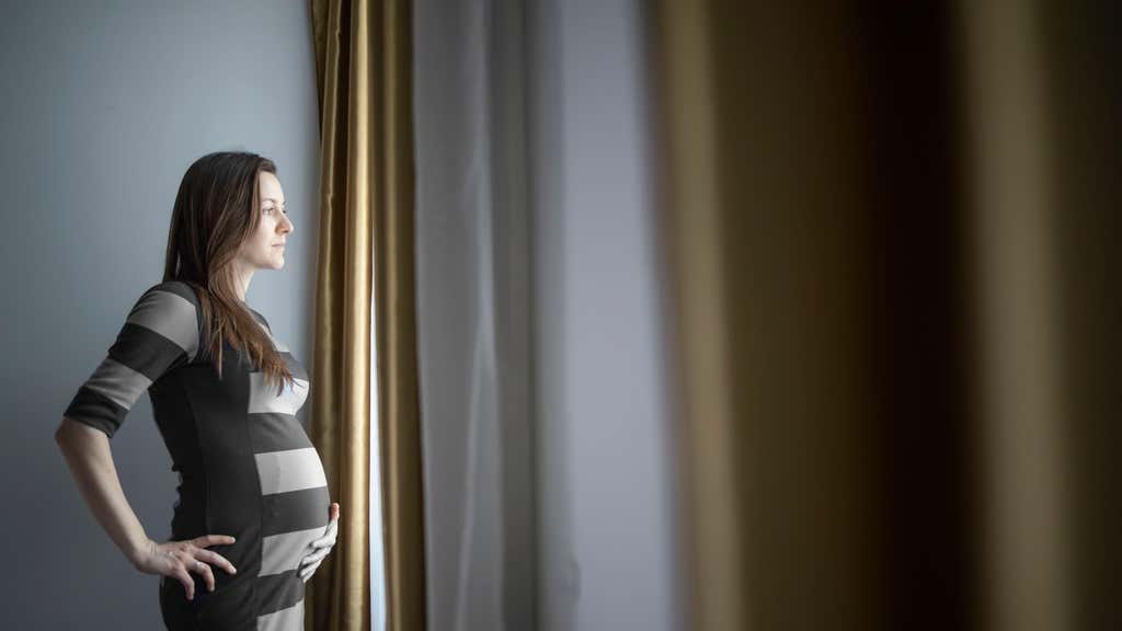 A pregnant woman looking out of a window
