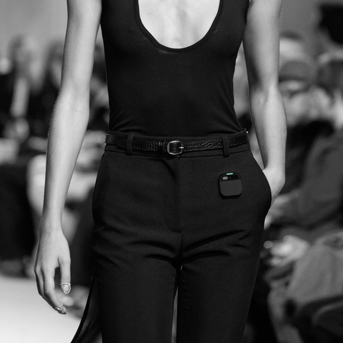 front profile of a model wearing Coperni tailored black trousers and top from their Spring Summer 2024 collection with the Humane Ai Pin floating near left hip pocket