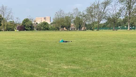 Child lying down in the middle of a park