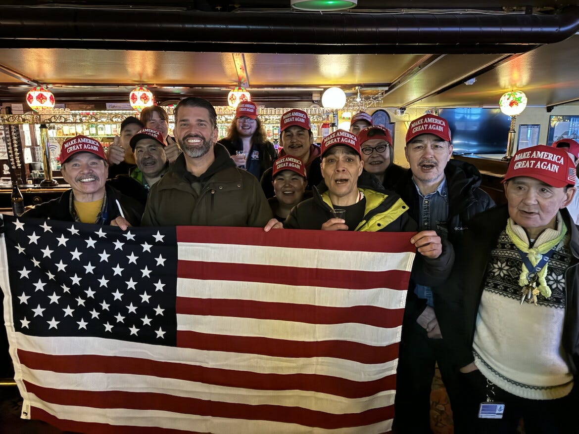 Donald Trump Jr. with a group of people holding an American flag.