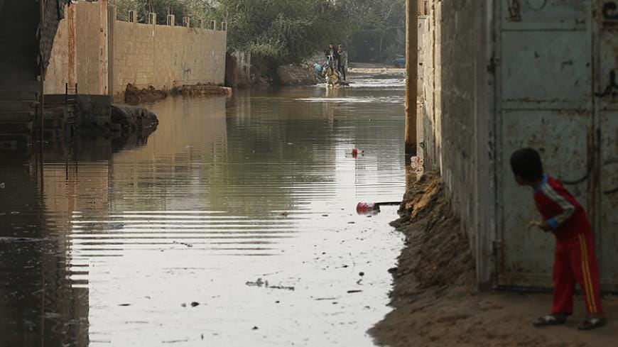 A boy looks at Palestinians as they ride a horse cart on a street flooded with sewage water from a sewage treatment facility in Gaza City November 14, 2013. Gaza municipality said they could not operate the sewage treatment facility due to shortages in fuel and power. Gaza's lone power plant shut its generators on November 1, 2013 due to a fuel shortage, a move that will likely increase already long blackout hours in the impoverished coastal territory run by the Islamist Hamas group. Power is provided to di