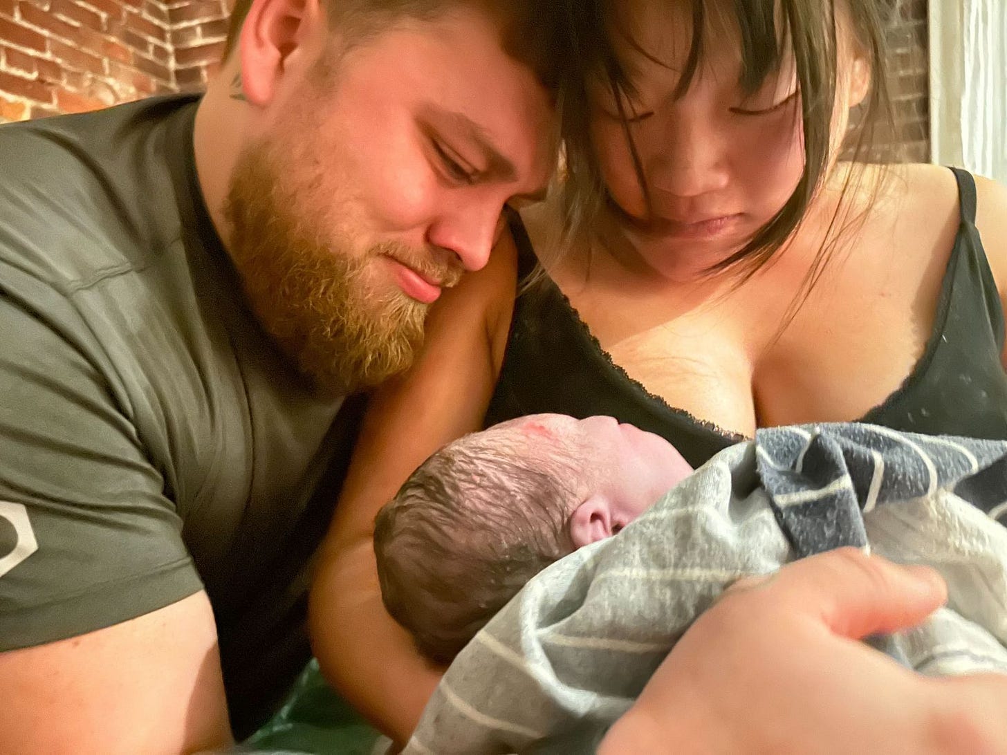 Katelin Potter-Rivera and her husband admire their newborn baby.