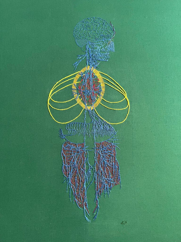 An image of an old engraving of a vagus nerve is embroidered on green cotton. The gut is in a large bamboo embroidery hoop. The embroidery of the main nerve lines is done in blue chain stitch in perlé cotton. The brain and some of the face is stitched in the same thread in backstitch. Details in the face are stitched in single strand floss. A bright red anatomical heart is stitched in red whipped back stitch. Around it a bright golden yellow halo in a vesica piscis shape is stitched in single strand thread. Three sets of ribs have are stitched in bright green/yellow stem stitch. There are some tiny details in different colours along some of the nerves. Burgundy roiling with sparse tiny black French knots are stitched in the gut area. The nerve endings in the diaphragm area are lengthened with one and two strand whipped back stitch. Lia’s initials are stitched in green thread in the bottom right.An image of an old engraving of a vagus nerve embroidered on green cotton. The main nerve lines are in blue chain stitch in perlé cotton. The brain and some of the face is in the same thread in backstitch. Details in the face are in single strand floss. A bright red anatomical heart is in whipped back stitch. Around it a bright golden yellow halo in a vesica piscis shape is in single strand thread. Three sets of ribs are in bright green/yellow stem stitch. There are some tiny details in different colours along some of the nerves. Burgundy roiling with sparse tiny black French knots are in the gut area. The nerve endings in the diaphragm area are lengthened with one and two strand whipped back stitch. Lia’s initials are stitched in green thread in the bottom right.