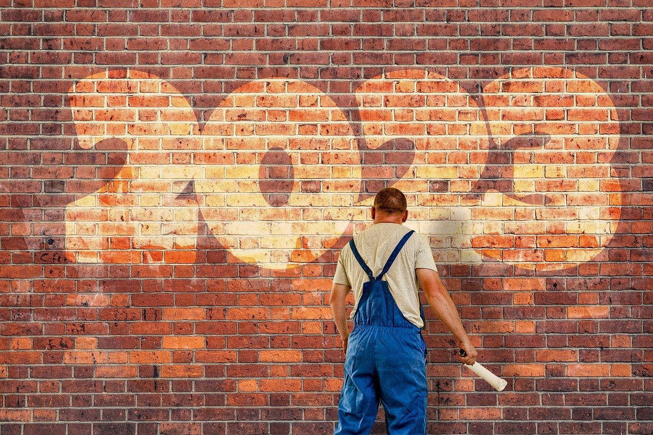 Painter facing brick wall with 2023 written on it.