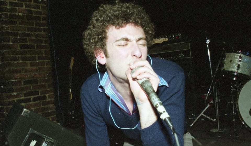 Adam Miller crouches while singing for The vOgue at Vancouver's Brickyard