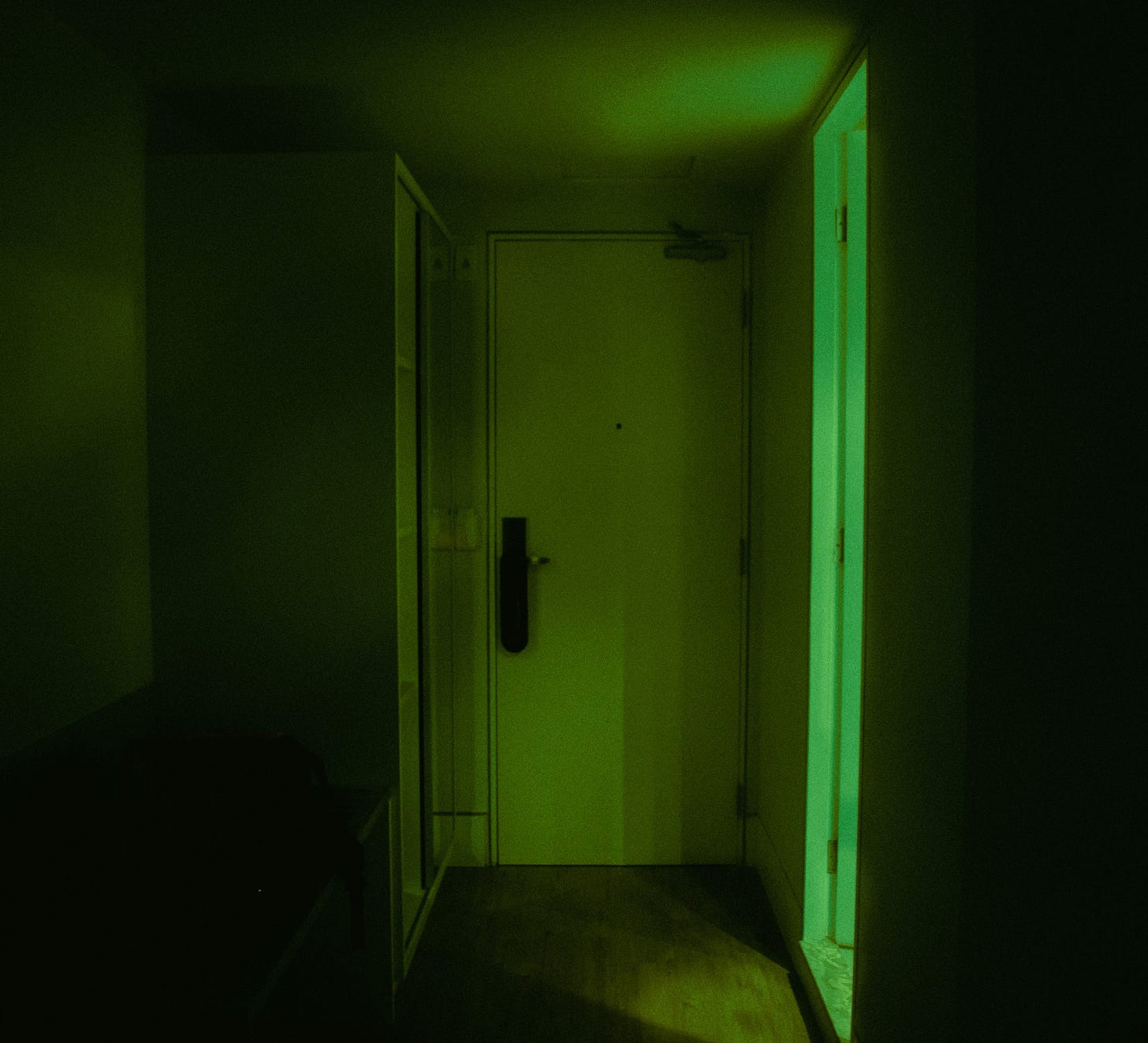 creepy green lit basement door down a dark corridor