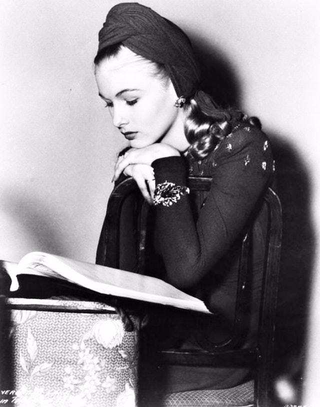 Black and white image of 1940s Hollywood star Veronica Lake reading a book