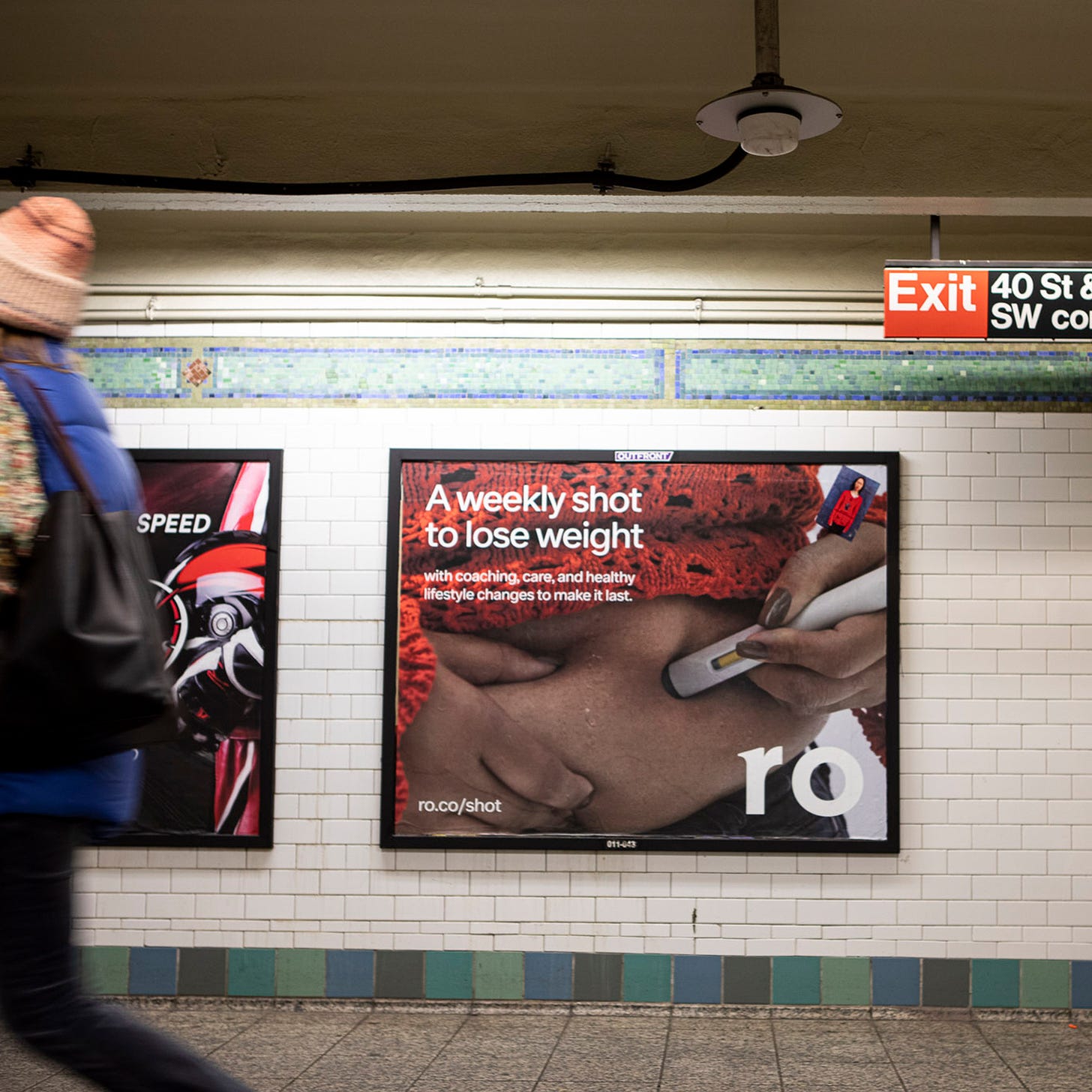 Photo of a subway entrance. A person is walking by an advertisement from the telehealth company Ro, showing a person injecting themselves with Ozempic. The ad reads “A weekly shot to lose weight”. 