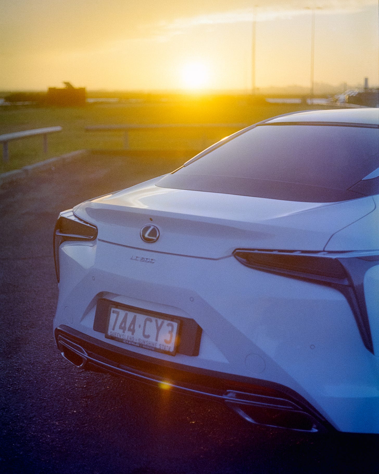 An LC500 Lexus with the glare of the sunset shining from the horizon