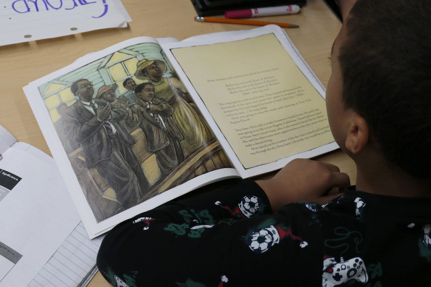 A book sits open on a table in front of a student.