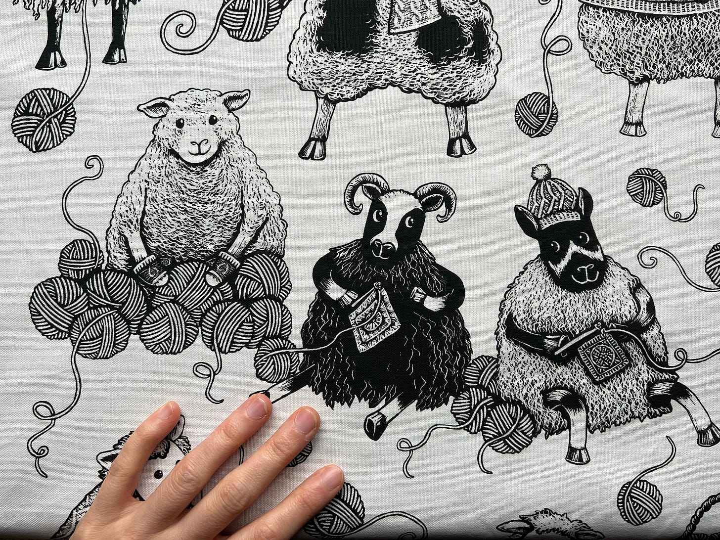 A close up of an illustrated tea towel. Three sheep sit in a row playing with yarn.