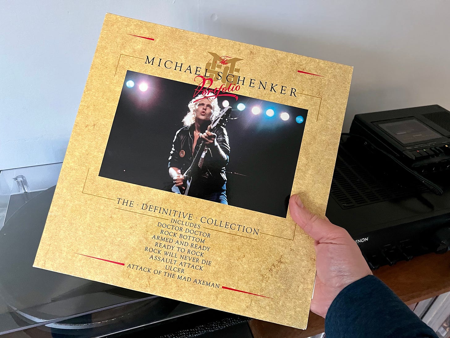 an album by Michael Schenker called the Michael Schenker portfolio is being held above a Project Carbon Record player
