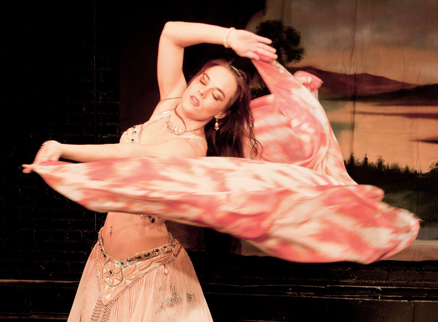 The author in a peach and silver costume, floating a white and coral silk veil around herself