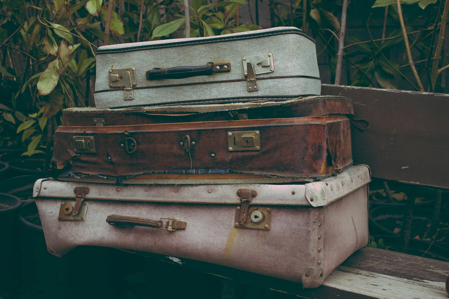 Three dilapidated suitcases on a bench