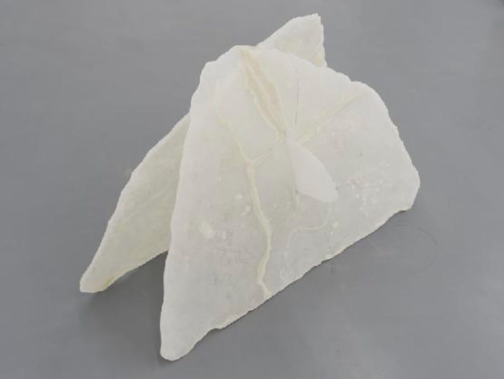 Two pieces of what look like stone appear to be resting on each other with a rounded piece that pierces another.