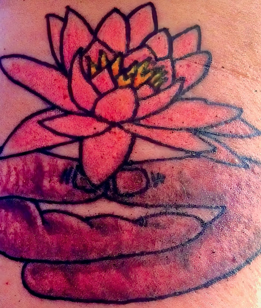 Tattoo of the Buddha's hands holding a lotus flower.