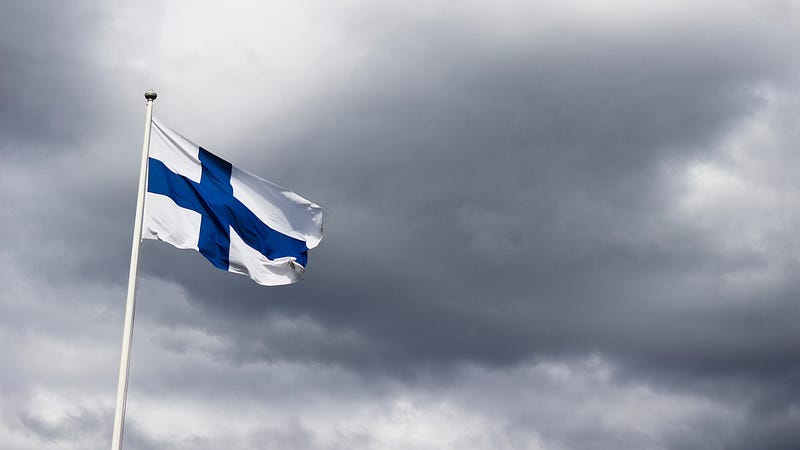 The Finnish flag in white and blue against a grey sky