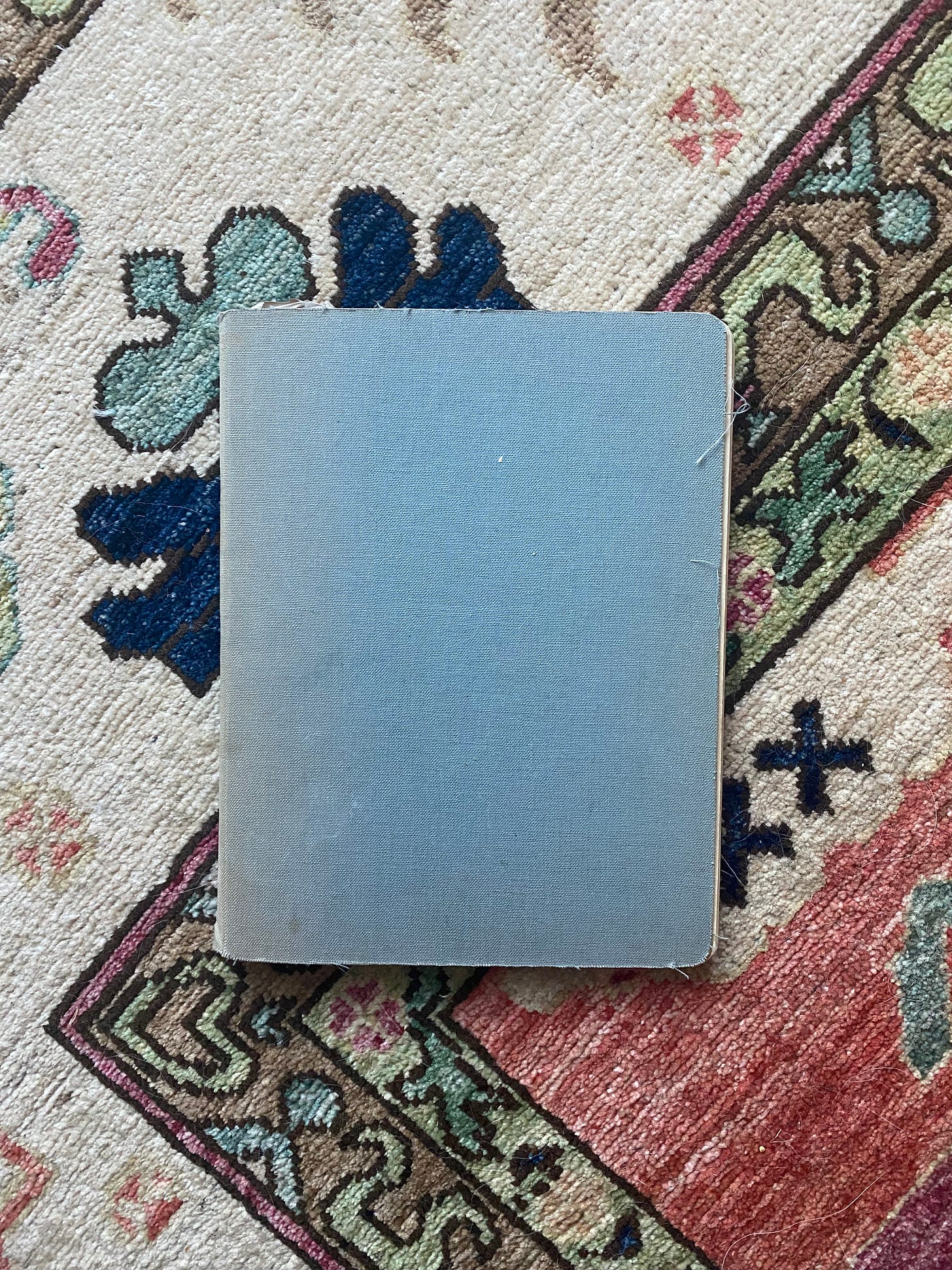 Photo of a faded blue hardcover notebook on a rug