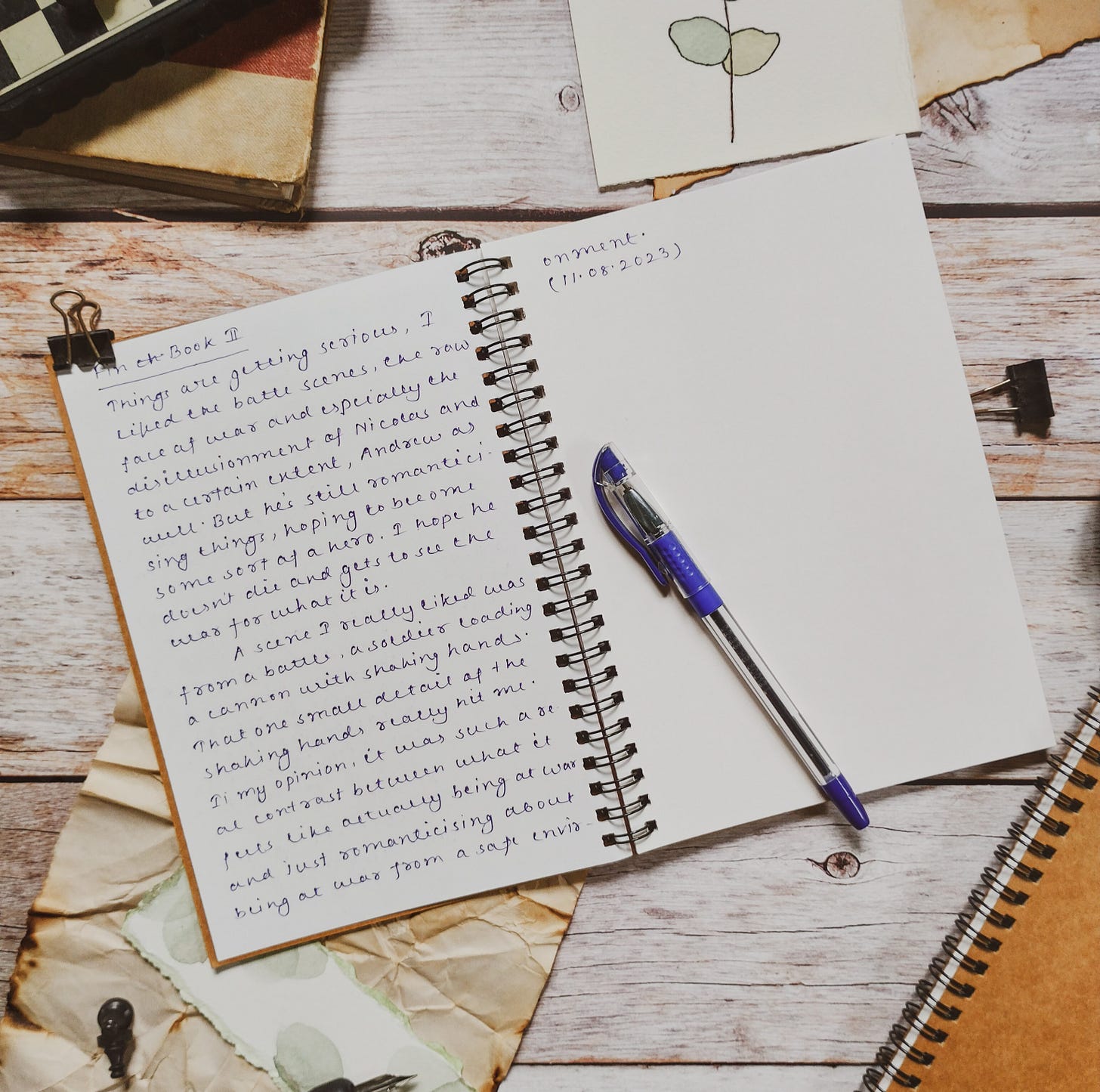 An open journal and a blue pen on a wooden table 