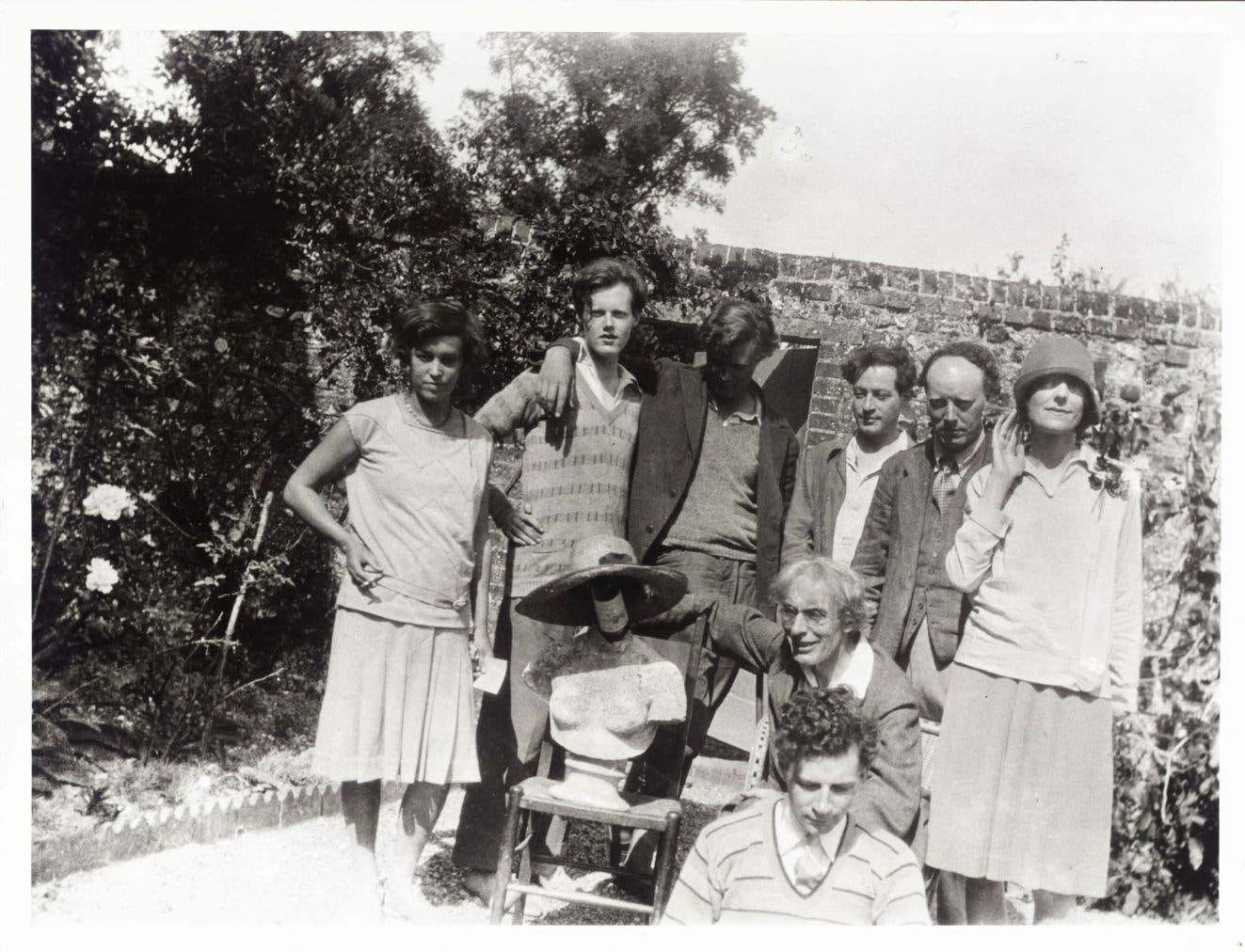 A black and white snapshot of the Bloomsbury group, eight writers and artists in a walled garden