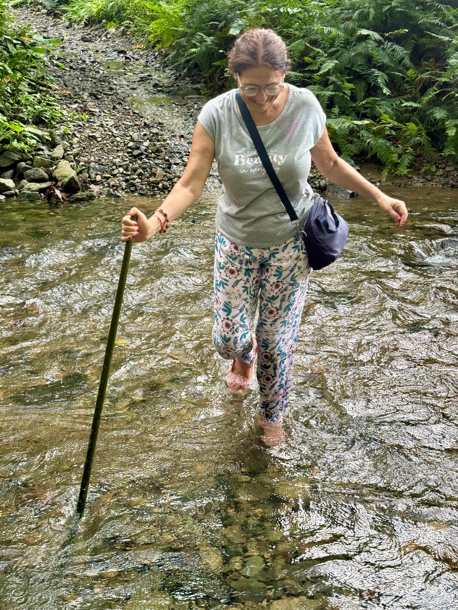 La autora cruzando un río de poca agua apoyada en un palo. Foto propia. 