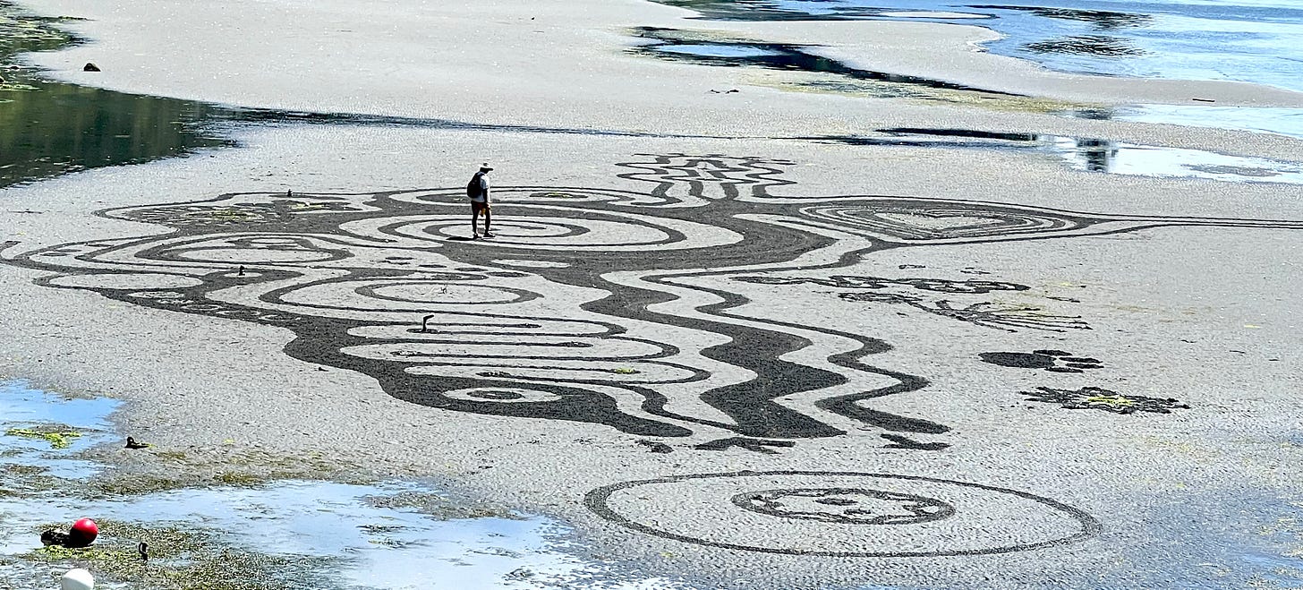 man on completed freeform labyrinth on beach