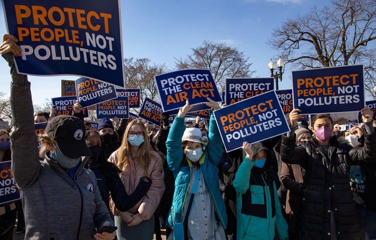 Climate change activists with masks and placards gather outside of the Supreme Court in Washington.