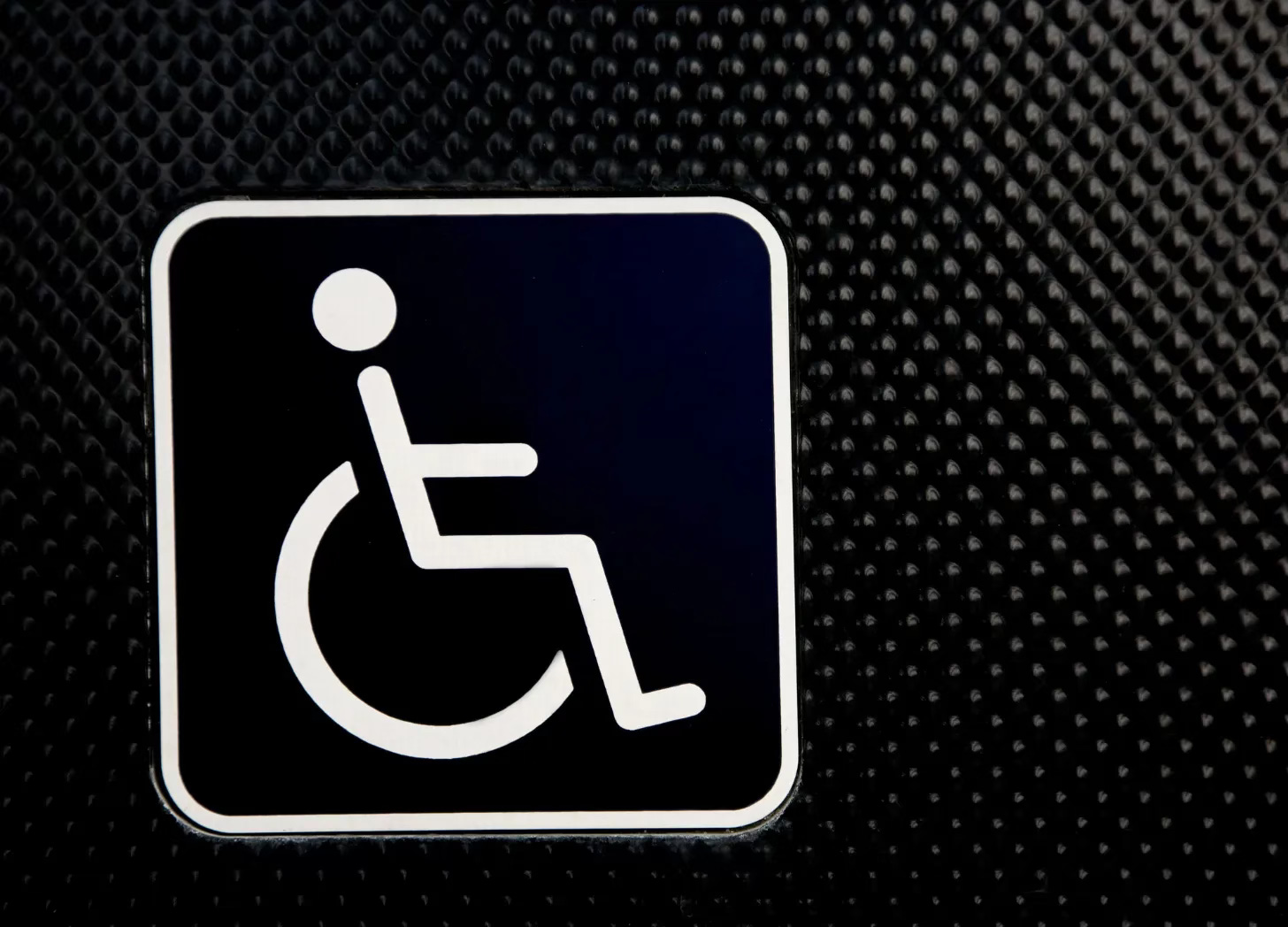 White wheelchair symbol on a black textured background