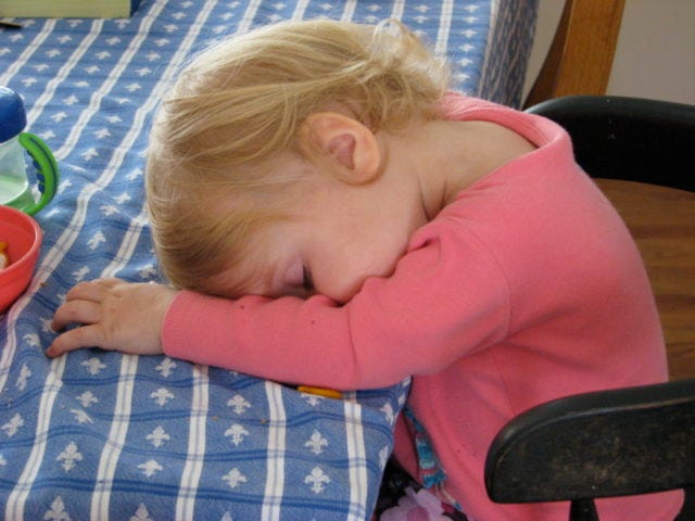 A toddler has fallen asleep at the table
